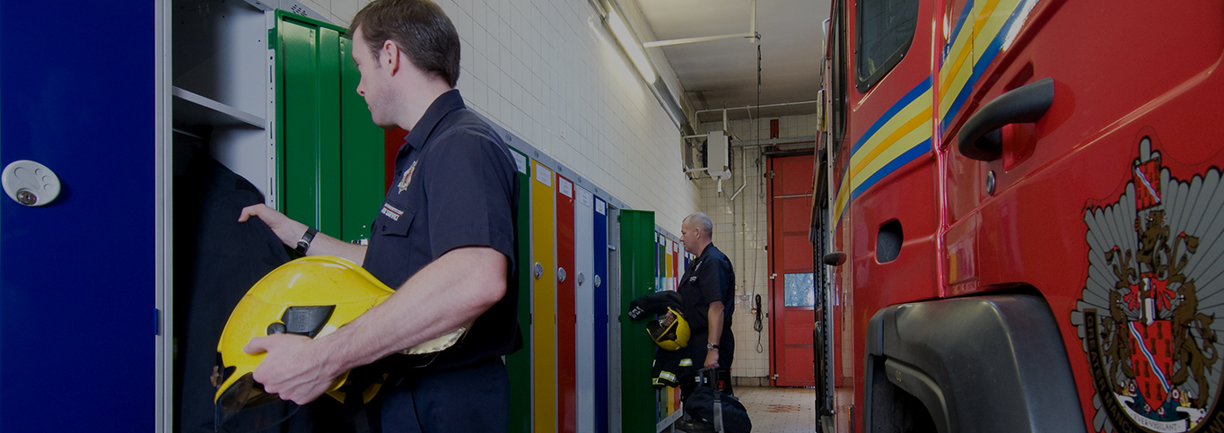 Image of firemen getting changed in a fire station using their lockers to get their clothes from.