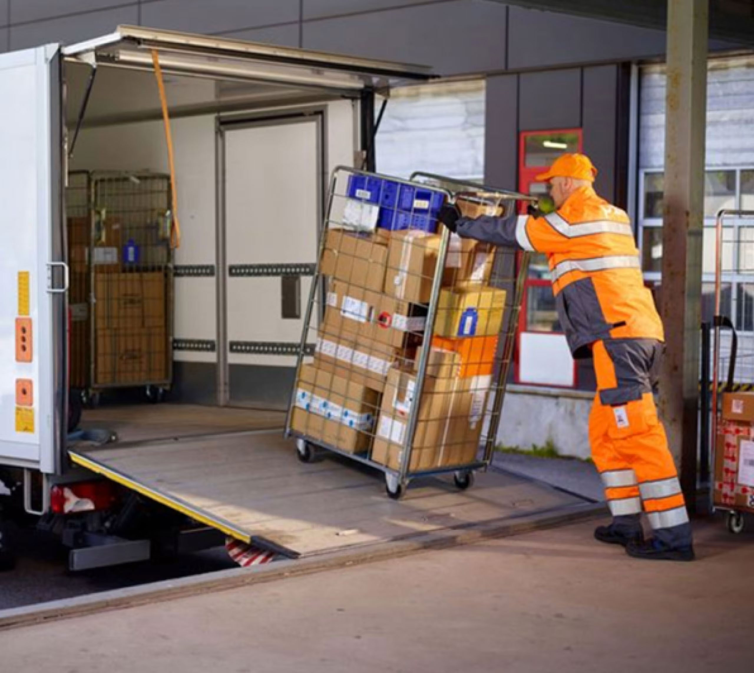 Man pushing roll pallet of post up on to a truck
